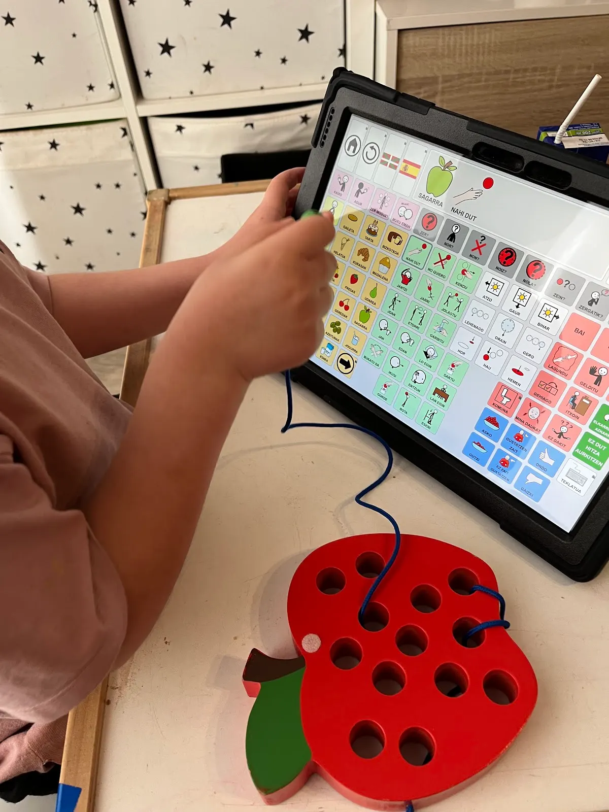 Una persona utiliza una tablet de comunicación junto a un tablero de actividades, en ABA Euskadi.