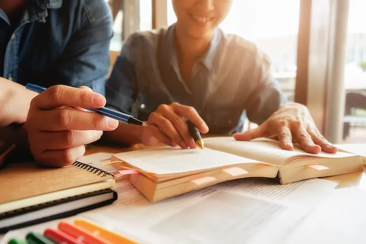 Personas estudiando juntas alrededor de un libro y tomando notas