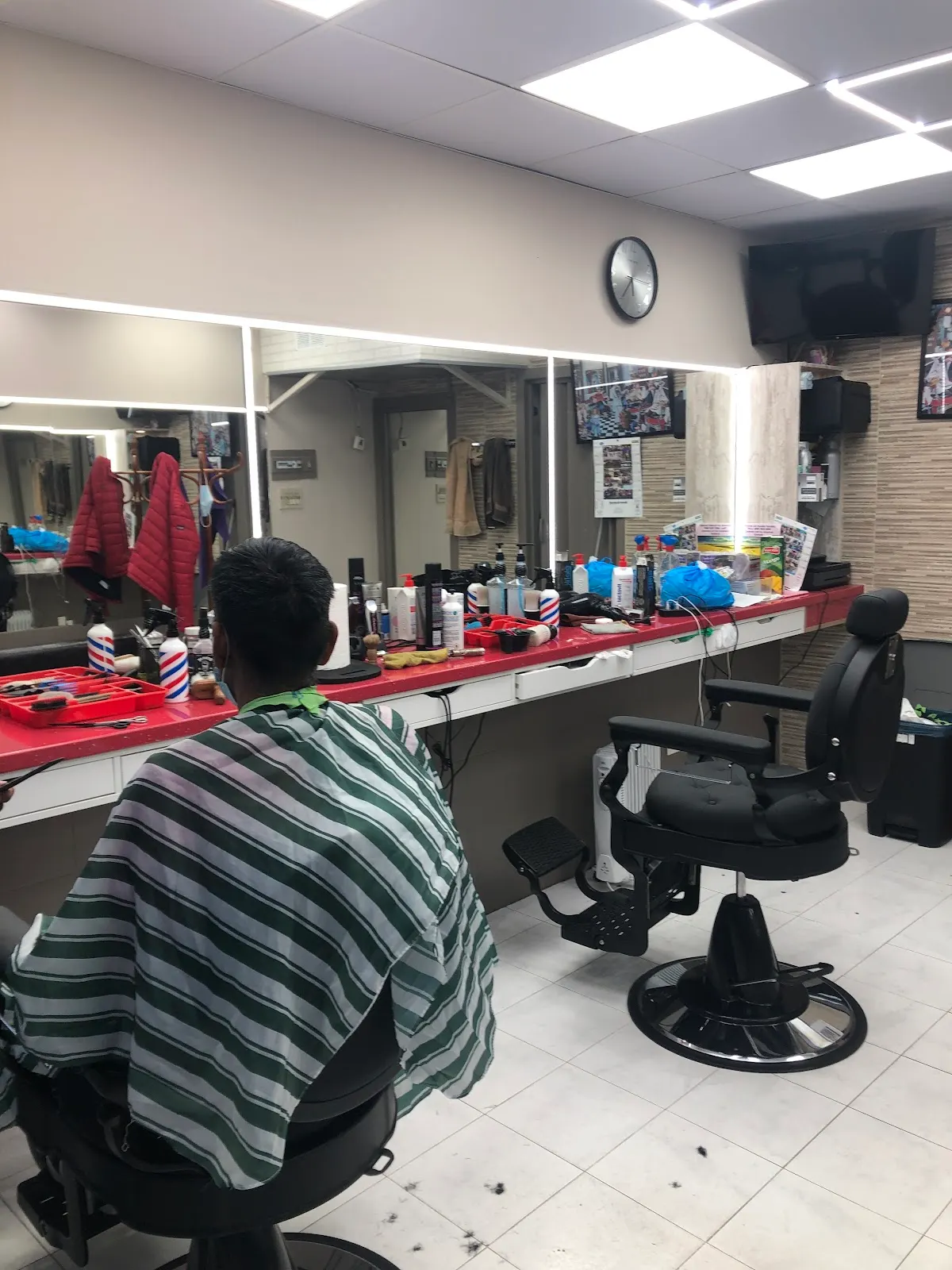 Interior de Adil peluquería con sillones de barbería y puestos de trabajo.