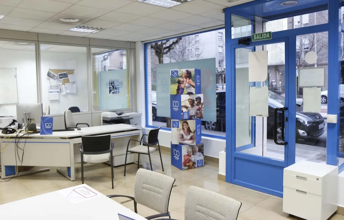 Interior de la Agencia de Santalucía Seguros, con mesas de atención y entrada acristalada.