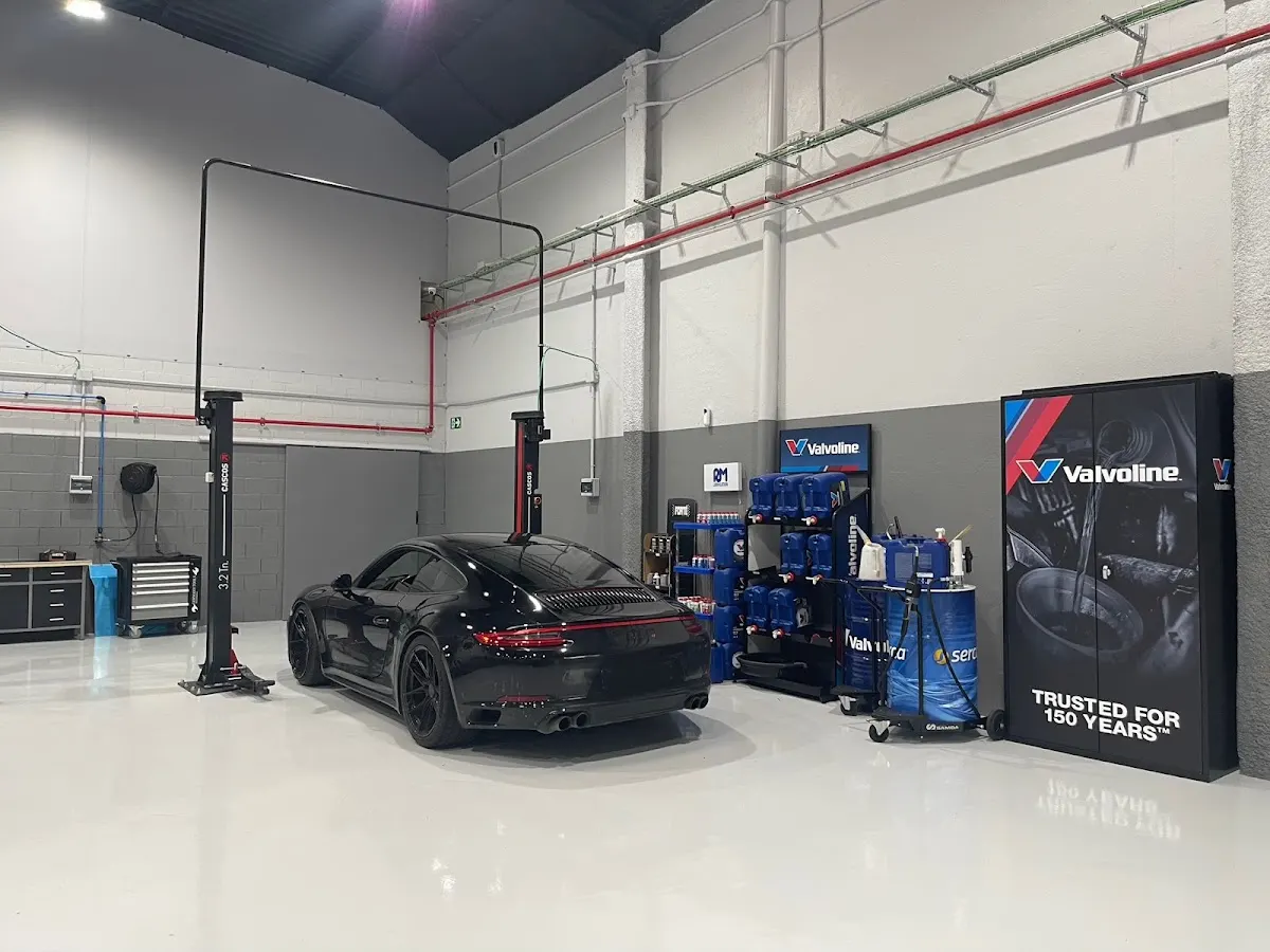 Interior del taller de AJ Motors Iurreta con un coche sobre elevadores y productos Valvoline.