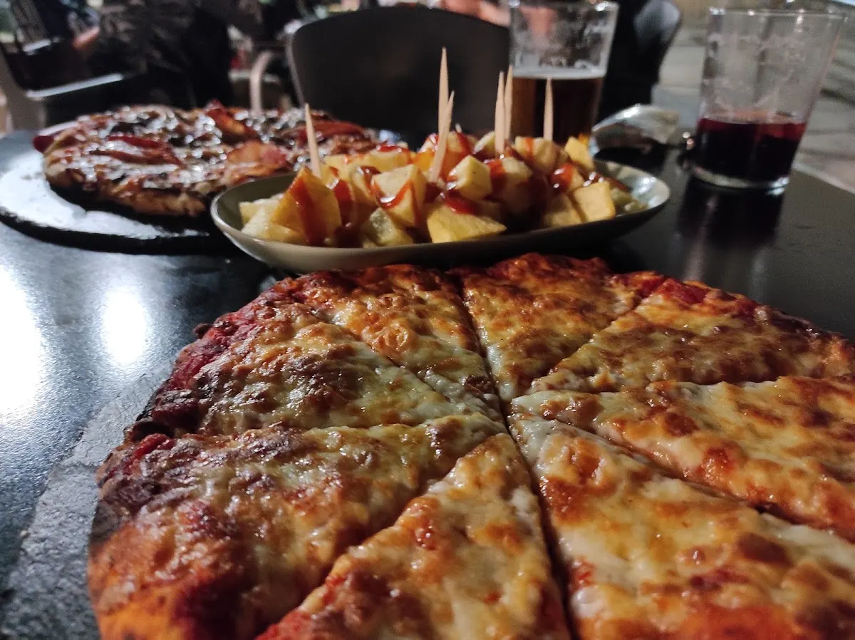 Pizza y patatas servidas en una mesa de Aledi...Bar.