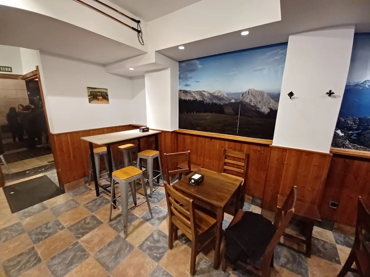 Interior de Alpino Taberna con mesas y sillas de madera.