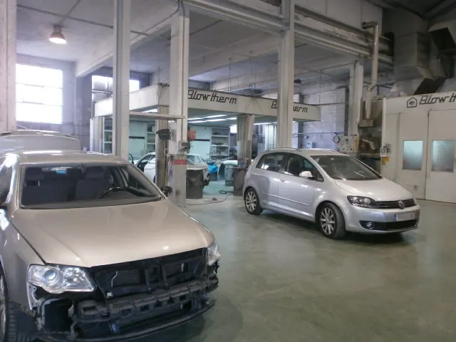 Interior del taller de AMAYA AUTO REPARACIONES, con varios coches en las zonas de reparación.