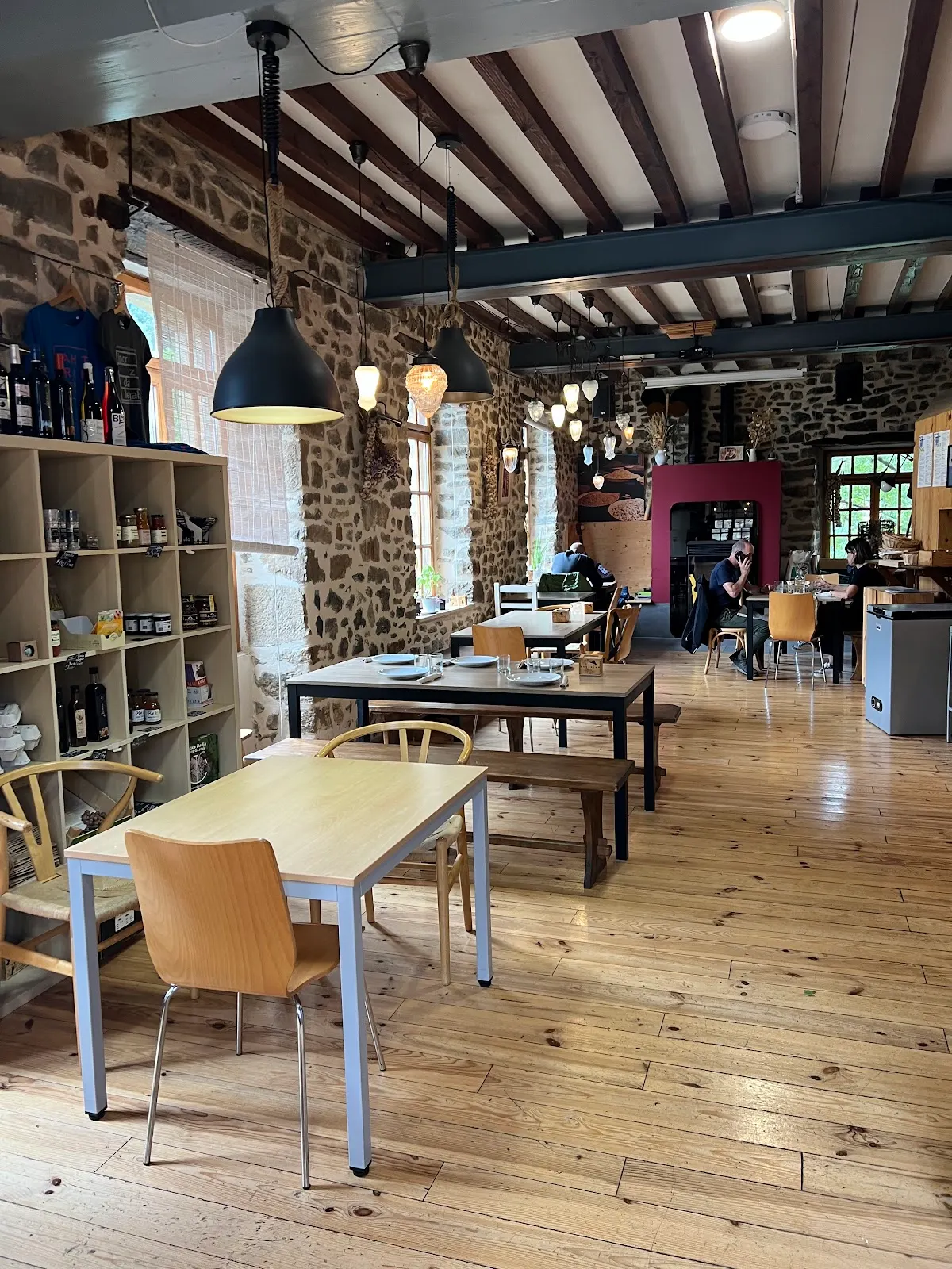 Interior de Amillena Arrazolako benta, con mesas de madera y paredes de piedra.