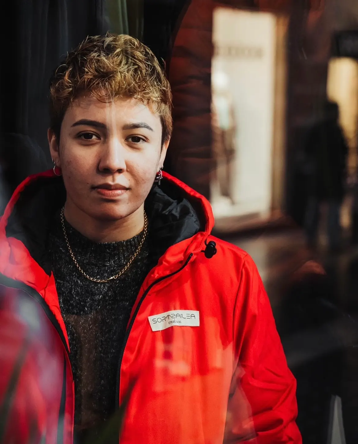 Retrato de Ana Dos Santos con una chaqueta roja en una calle.