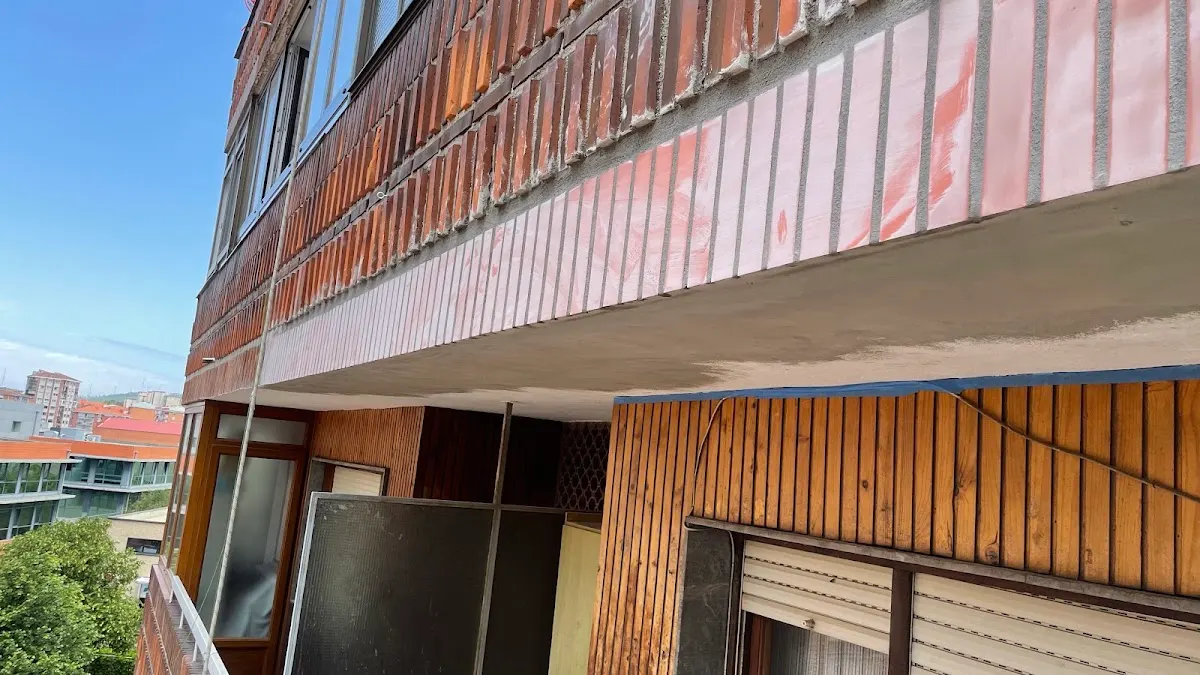 Fachada de edificio con balcones y revestimiento de ladrillo, en una imagen asociada a Arima Lan Bertikalak.