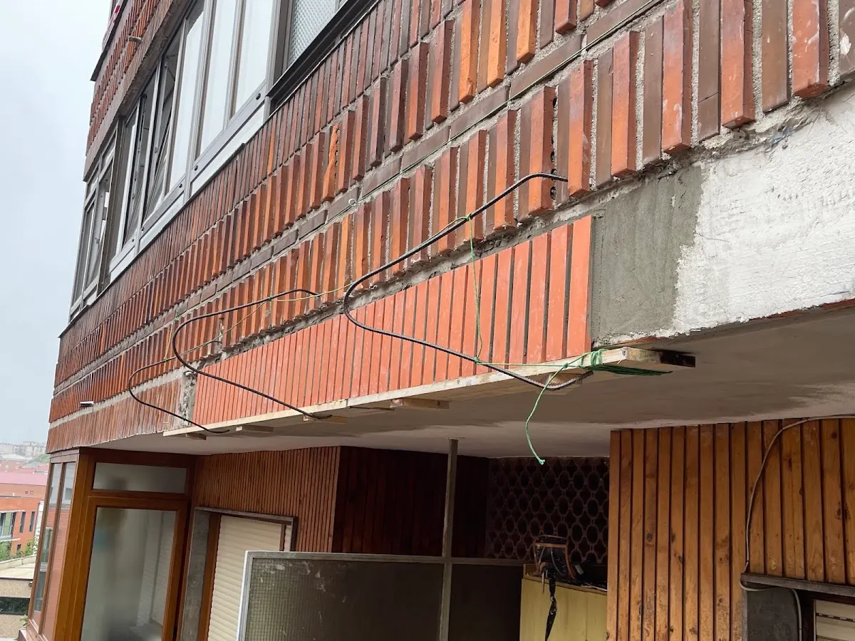 Detalle de una fachada de ladrillo con zonas de revestimiento deteriorado.