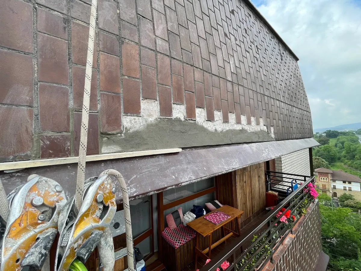 Trabajos en el exterior de un edificio, junto a una fachada y un balcón.
