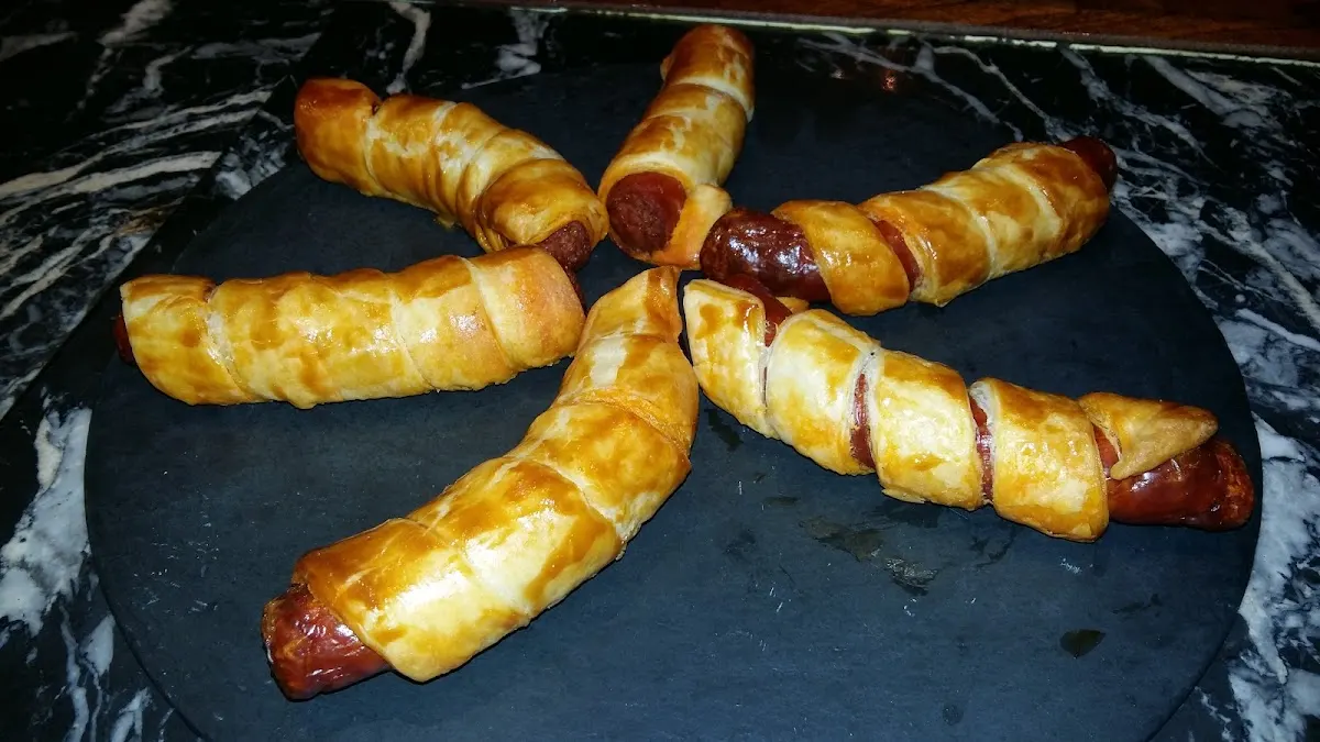 Salchichas envueltas en hojaldre sobre una bandeja, en Arkarazo Taberna.