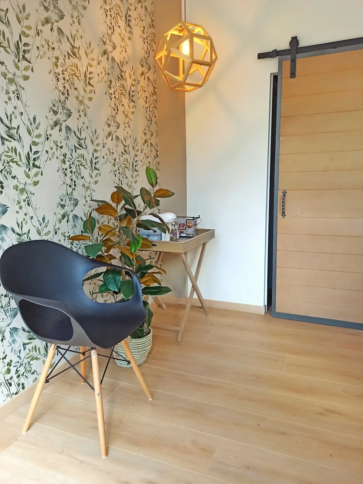 Espacio de espera de ATTEstudio, con una silla, plantas y una puerta de madera.