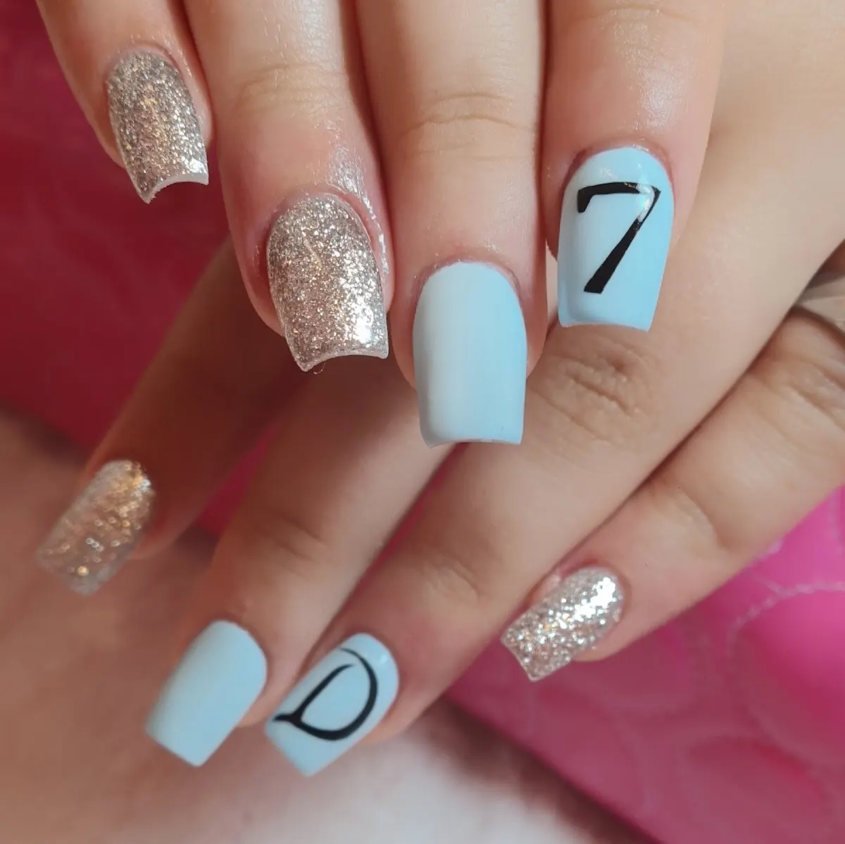 Uñas con esmalte celeste, purpurina y diseños gráficos, de Attica Nail Lounge.