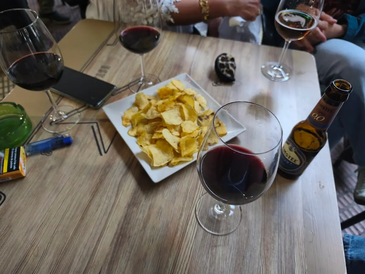 Vasos de vino, cervezas y patatas fritas sobre una mesa.