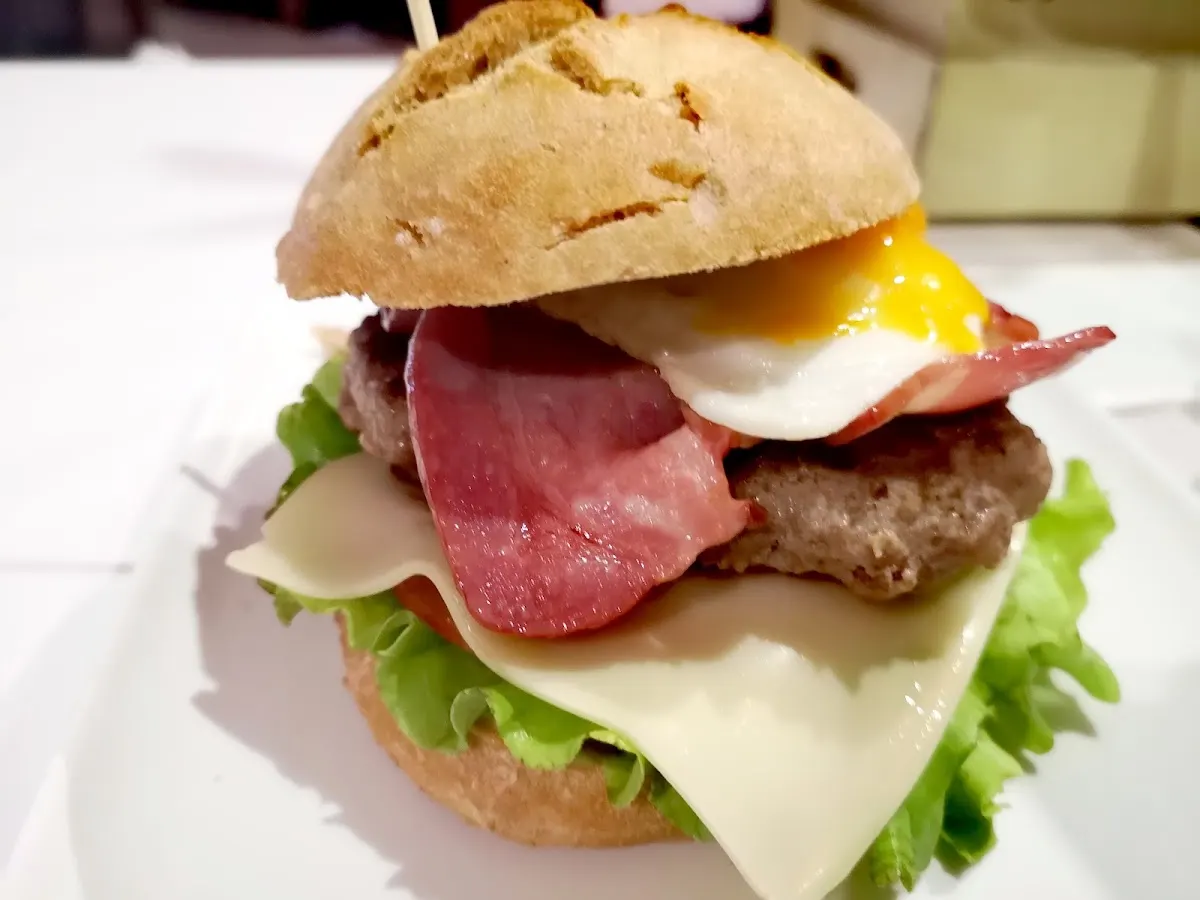 Hamburguesa con huevo, queso, lechuga y otros ingredientes, servida en Bar Goxoa.