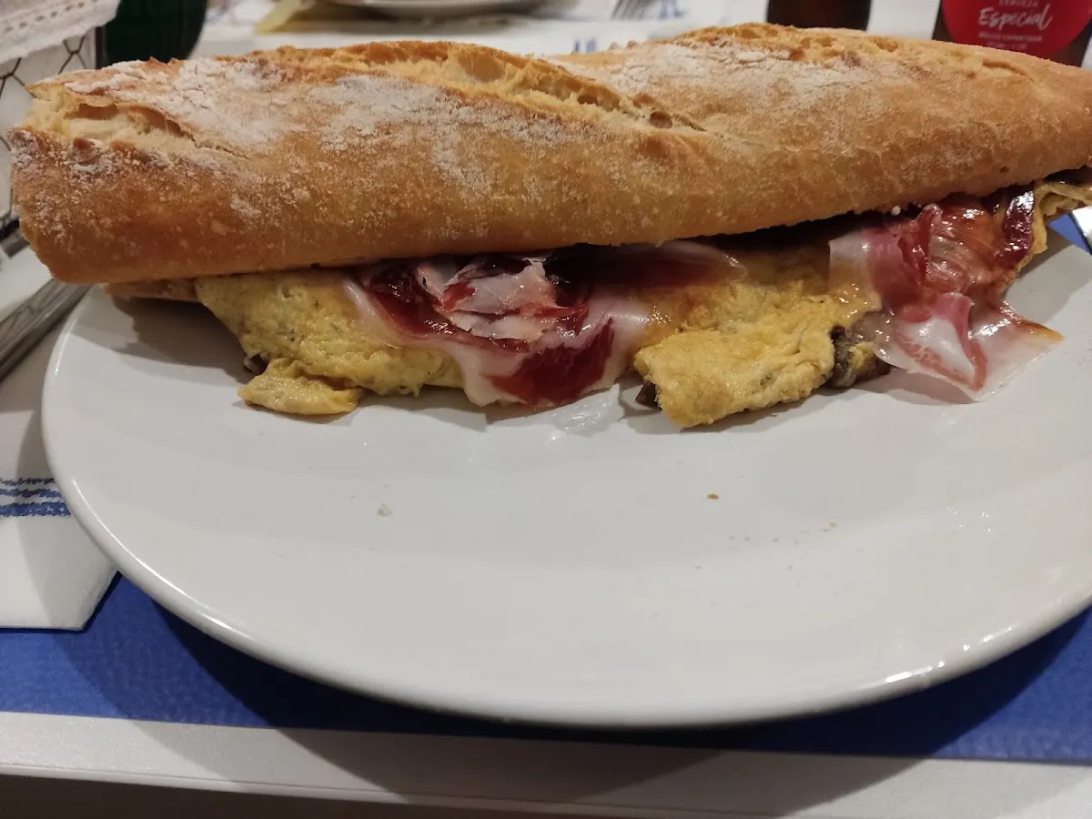 Bocadillo de pan crujiente con tortilla y otros ingredientes, servido en Bar Goxoa.