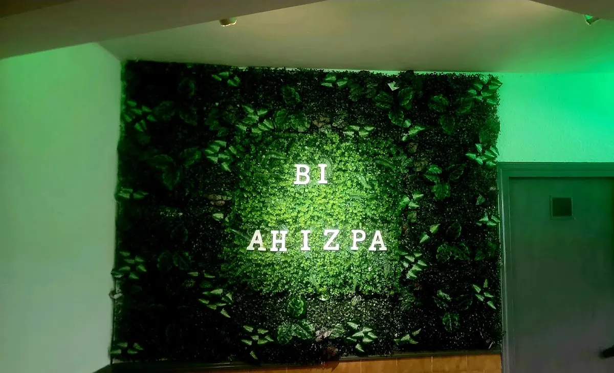 Entrada de Bi Ahizpa con pared vegetal e iluminación verde