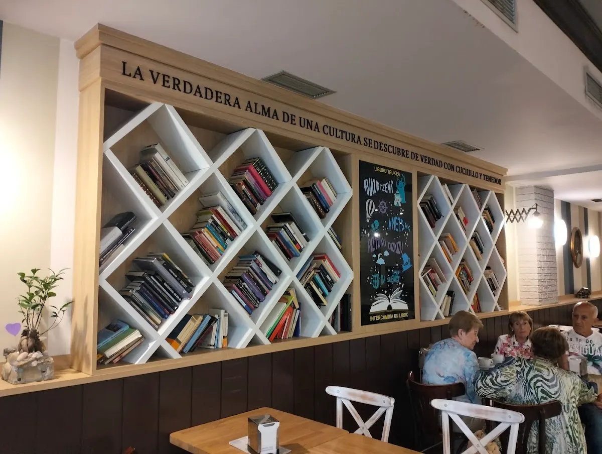 Interior de Bar Lezuri (Gambrinus), con estanterías de libros y mesas ocupadas.