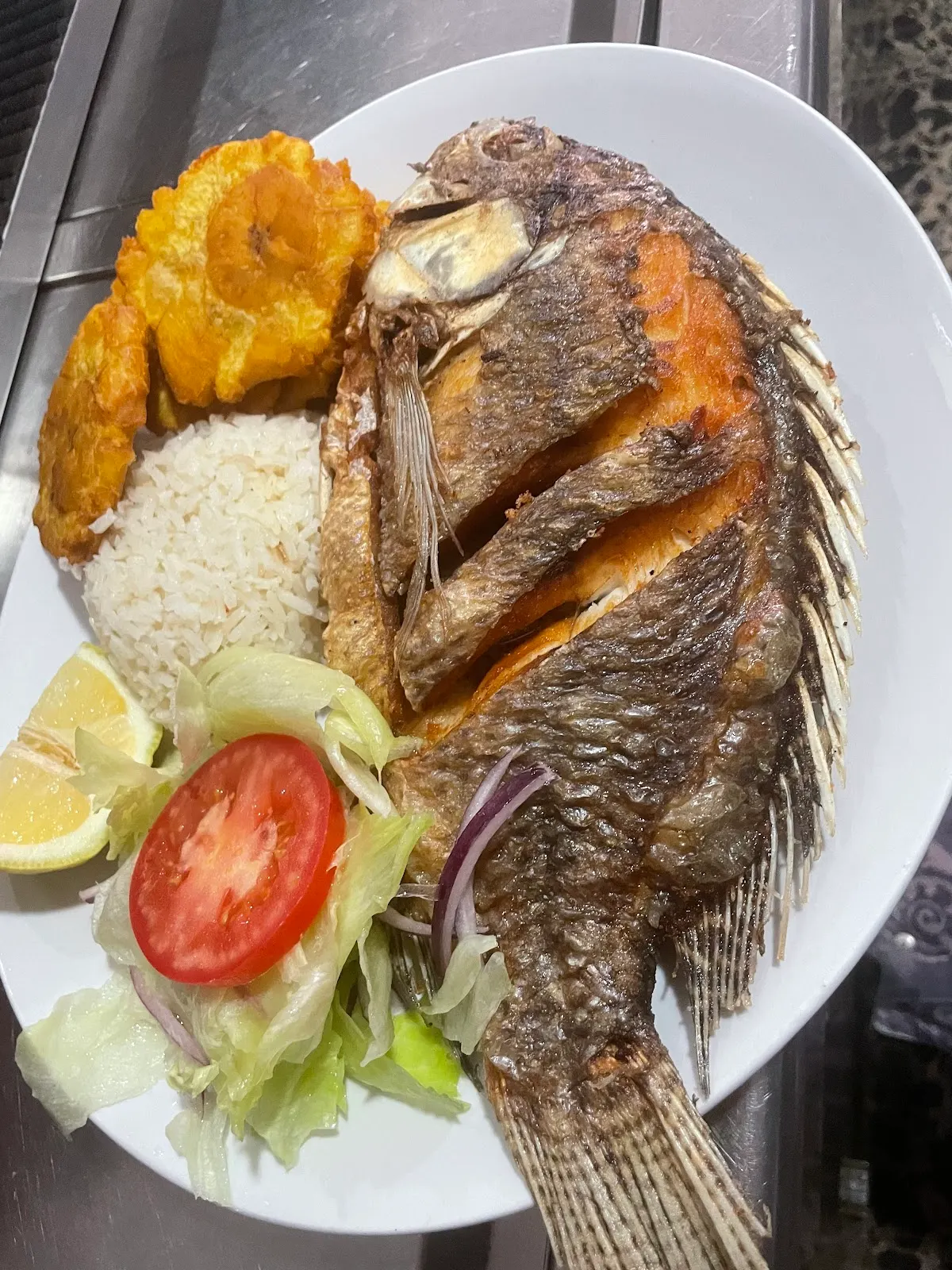 Pescado entero servido con ensalada y plátano en Bar Restaurante Silver City Cafe.