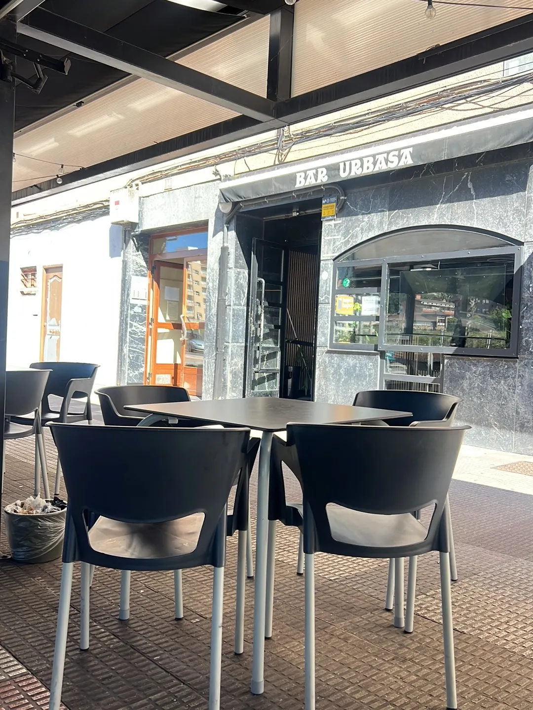 Terraza exterior de Bar Urbasa, con mesas y sillas frente a la entrada.