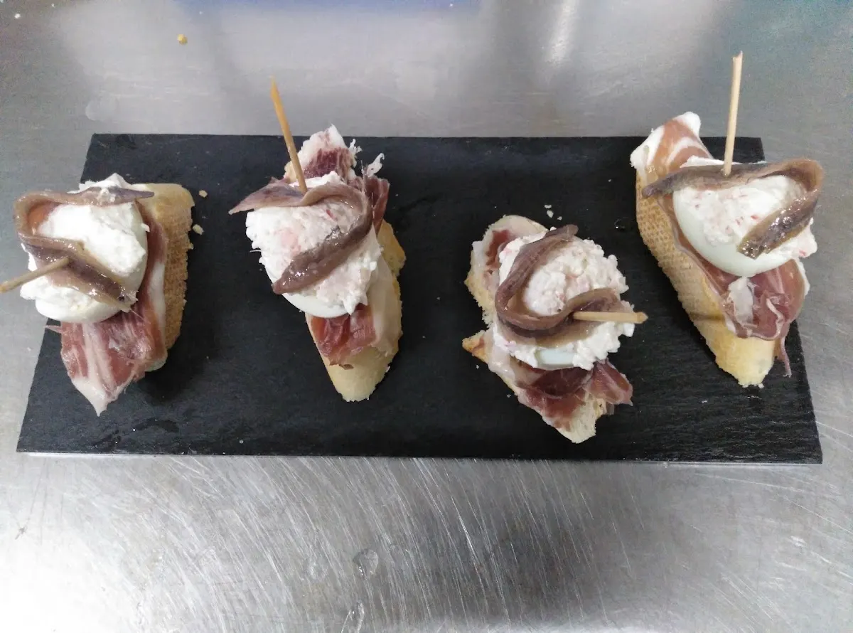 Pintxos de anchoa y otros ingredientes sobre una bandeja negra en Bar Vancouver