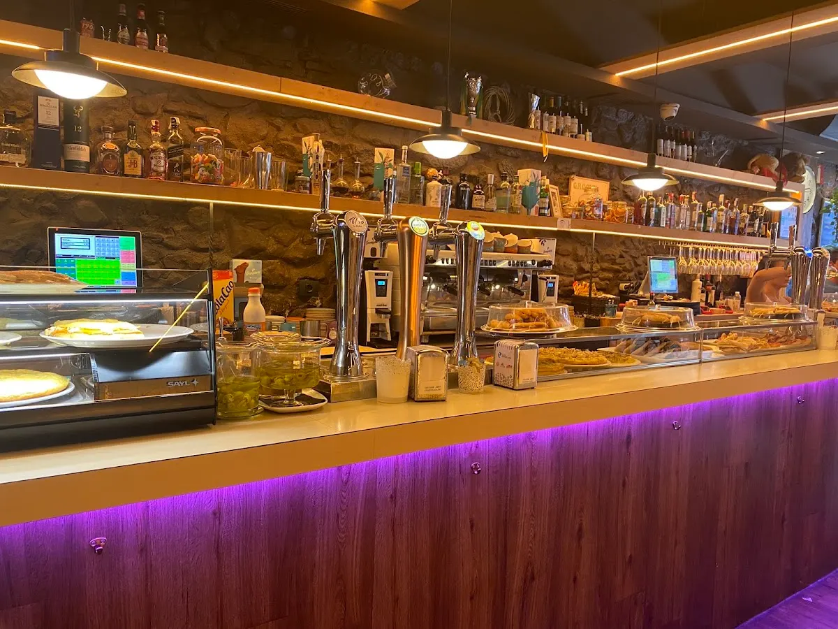 Barra de Bar Zero con grifos de cerveza, vitrinas y botellas en las estanterías.