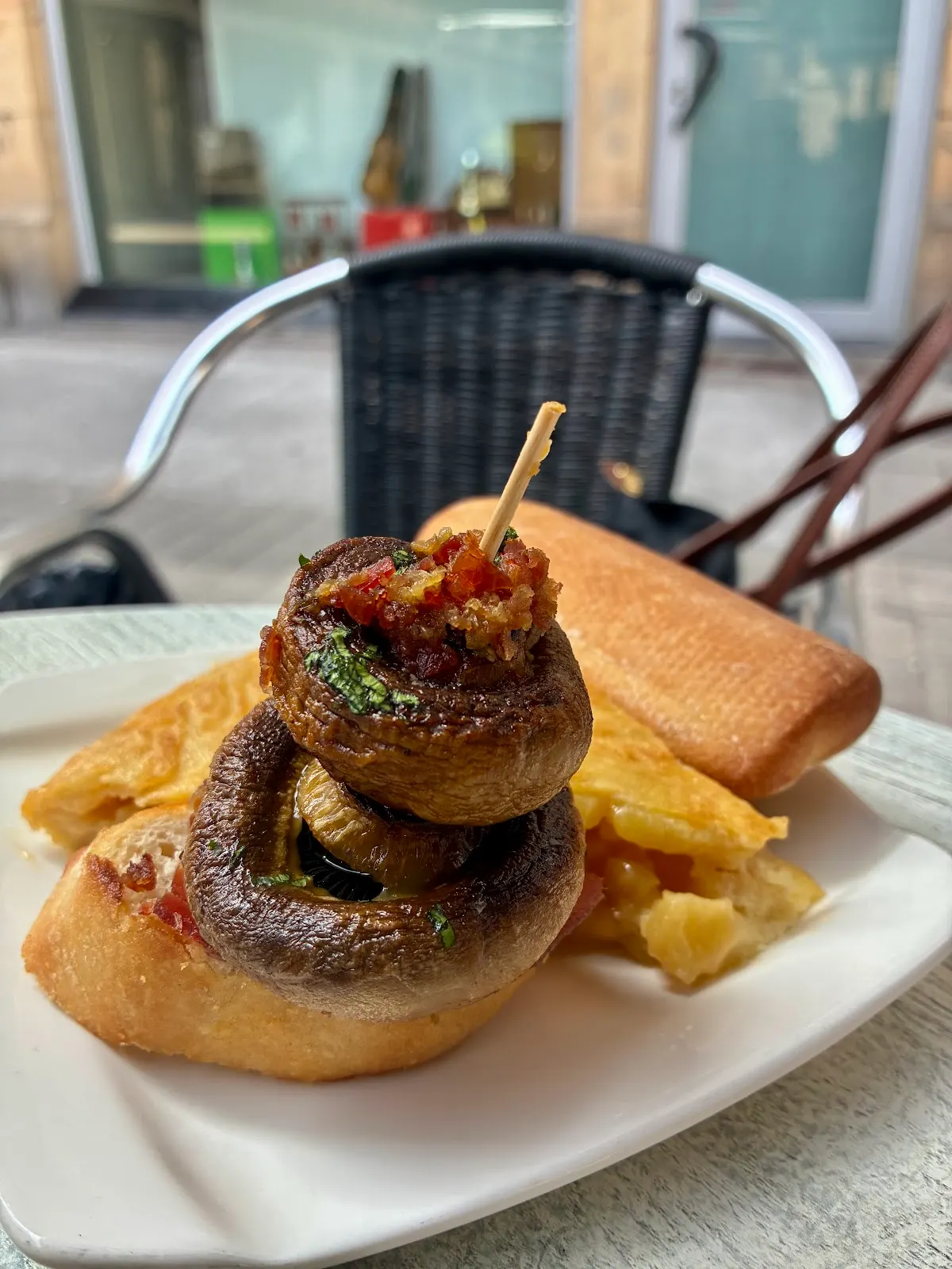 Pintxo de champiñones sobre pan, servido con patatas.