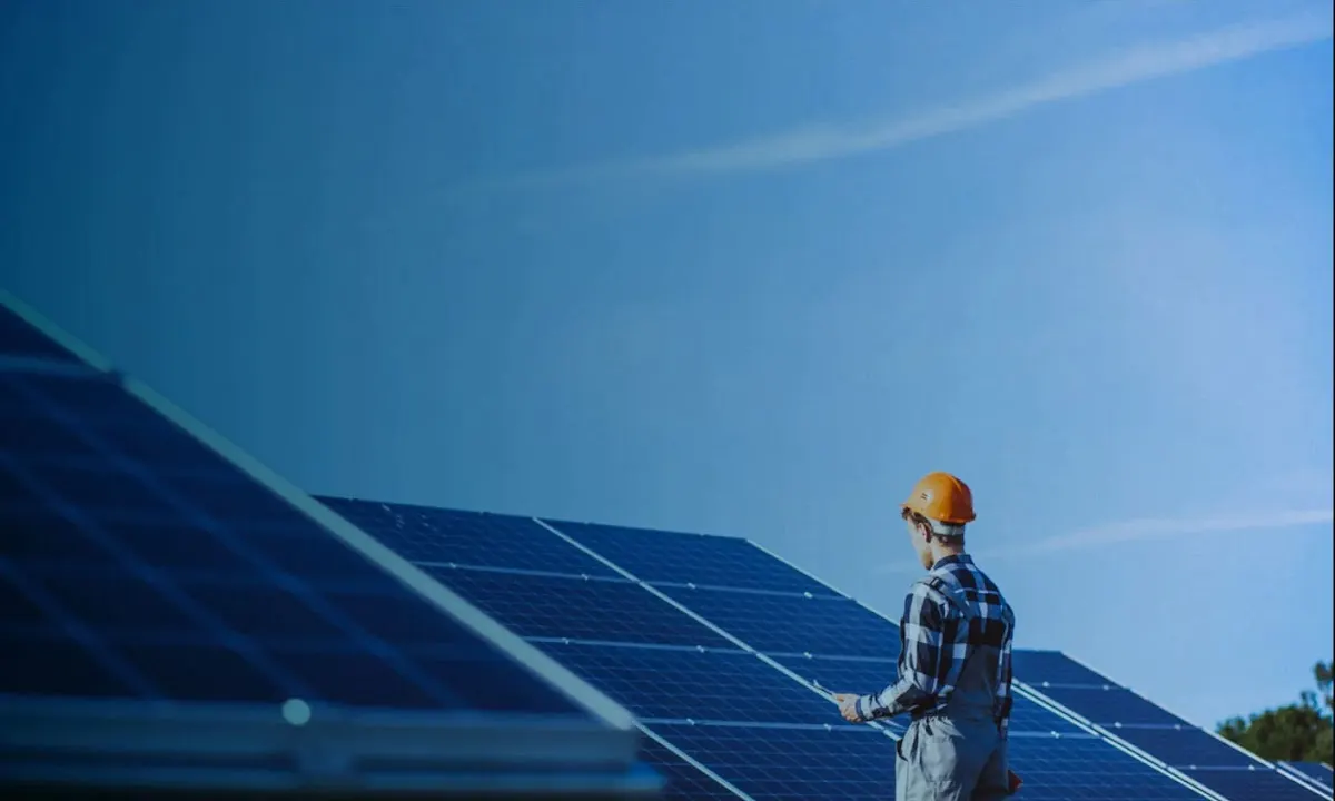 Técnico junto a paneles solares en una instalación exterior.