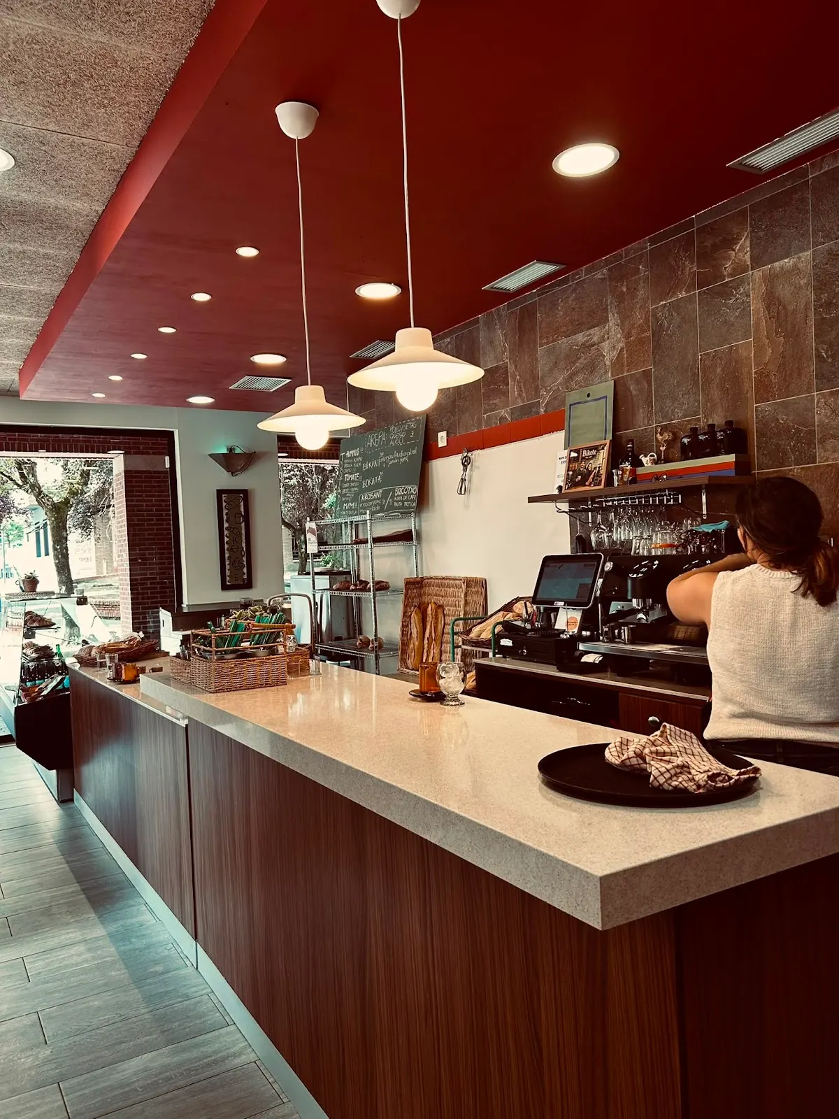 Interior de la cafetería BIKOTE, con barra, mesas y ventanales.