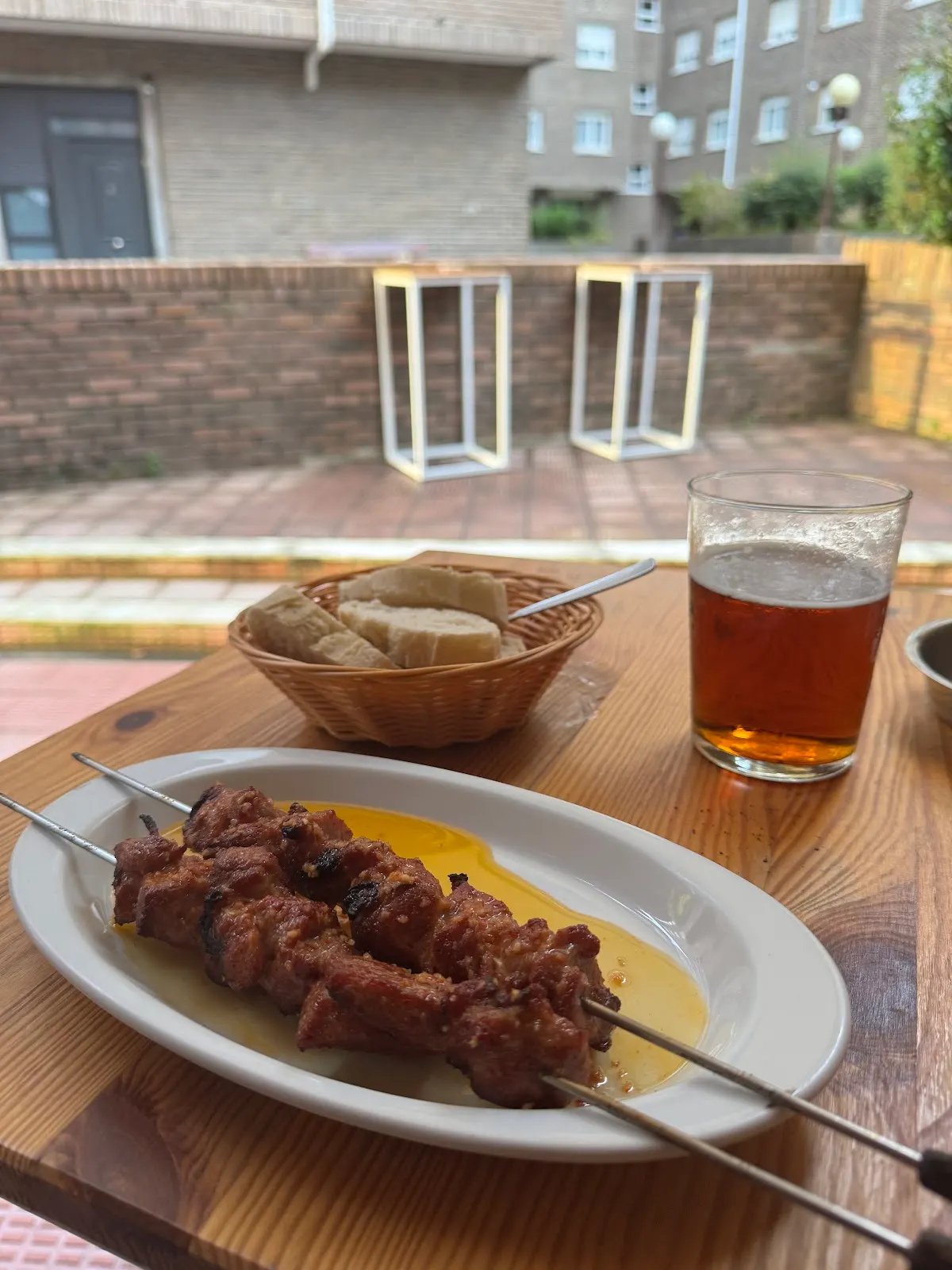 Pintxo moruno y bebida en una mesa exterior de Bodegón Landako