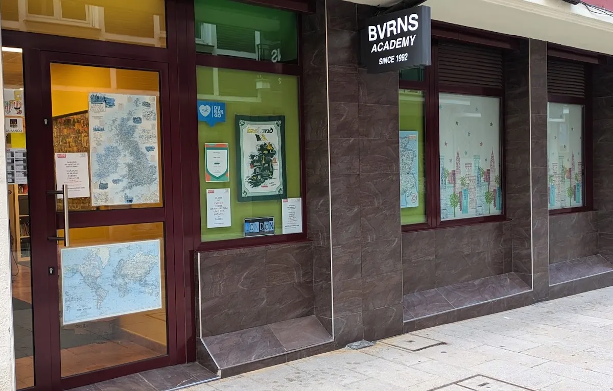 Fachada de Bvrns Academy en Durango, con carteles y mapas en los escaparates.