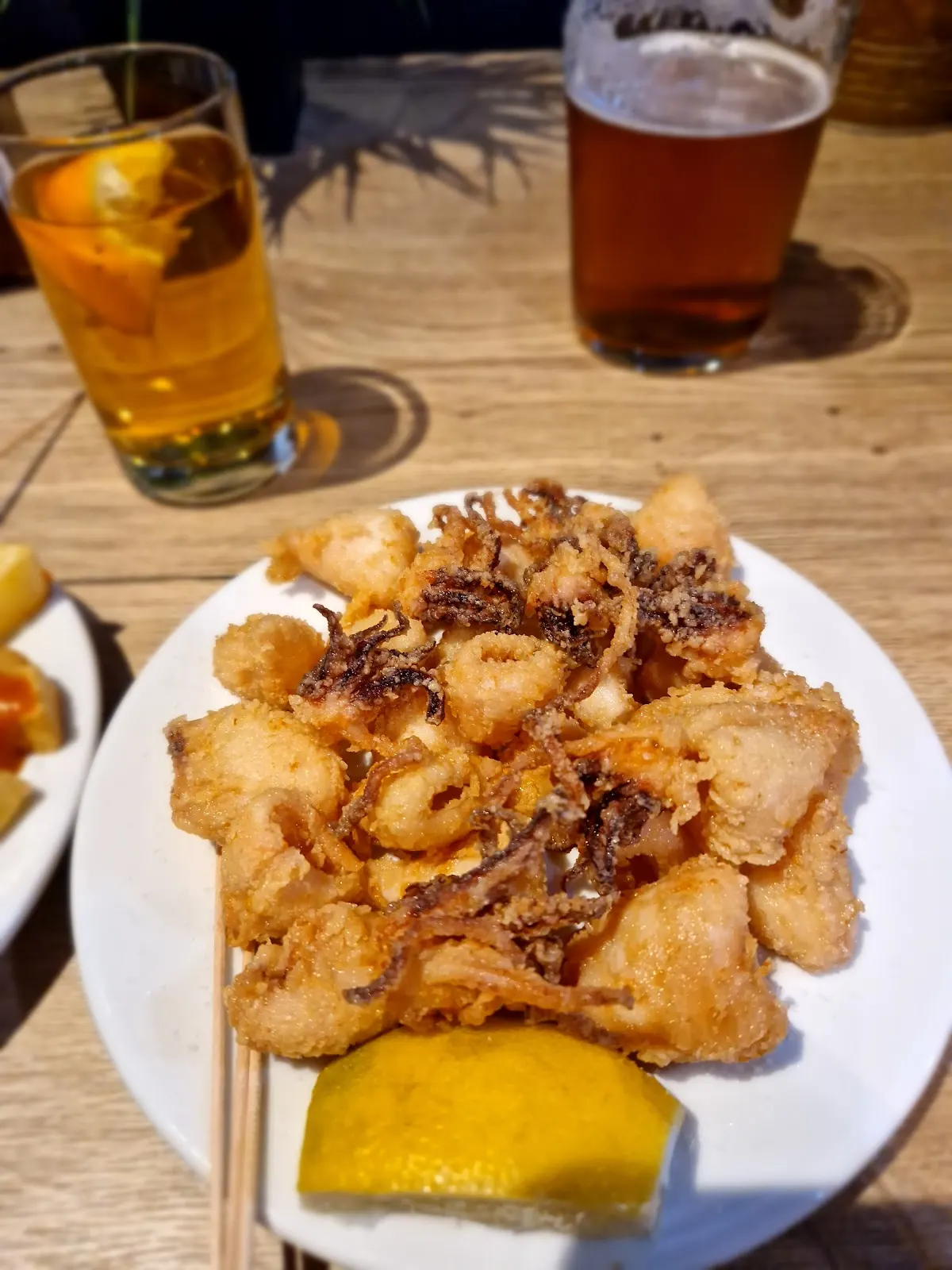 Rabas servidas en un plato en Cafe & Bar Elorza, junto a dos bebidas.