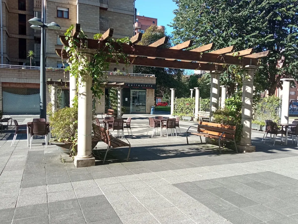 Terraza de la Cafetería El Parque junto a una plaza arbolada.