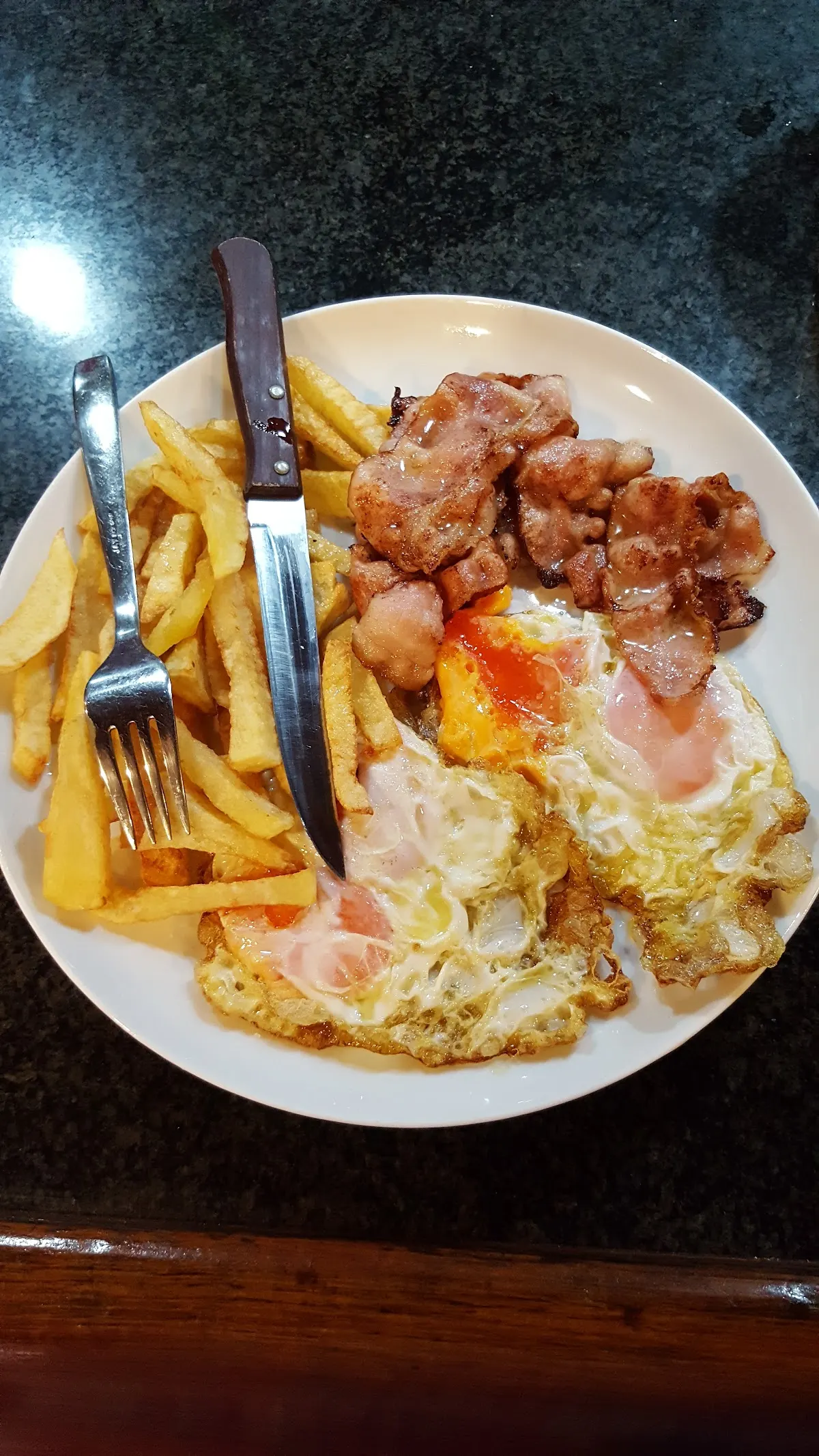 Plato de comida con huevos, patatas fritas y carne en Cafetería Ibai Ondo.