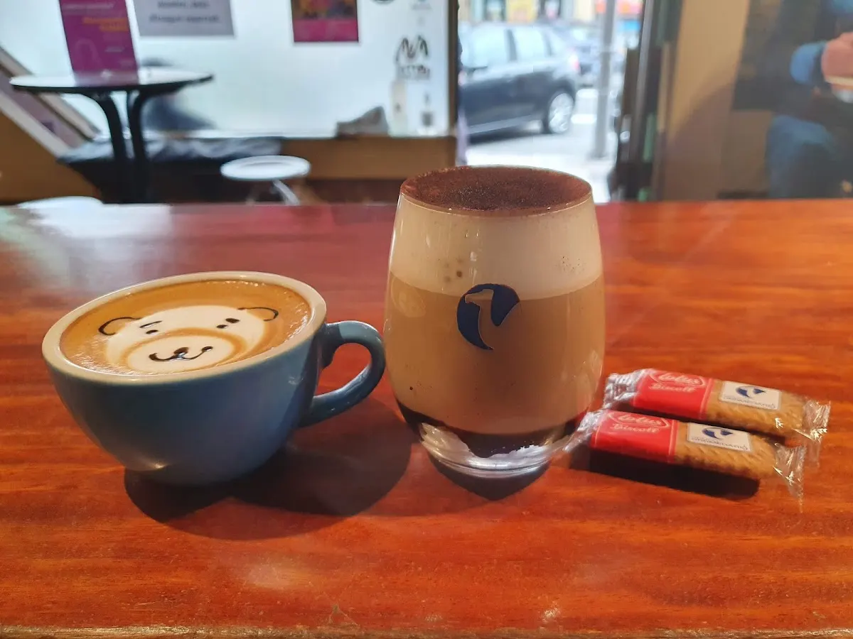 Cafés con dibujos en la espuma y galletas sobre la barra de Cafetería Uztargi