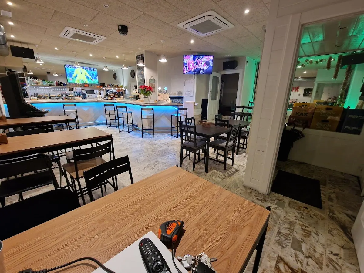 Interior de Cafetería Zubiertz, con mesas, sillas y barra iluminada.