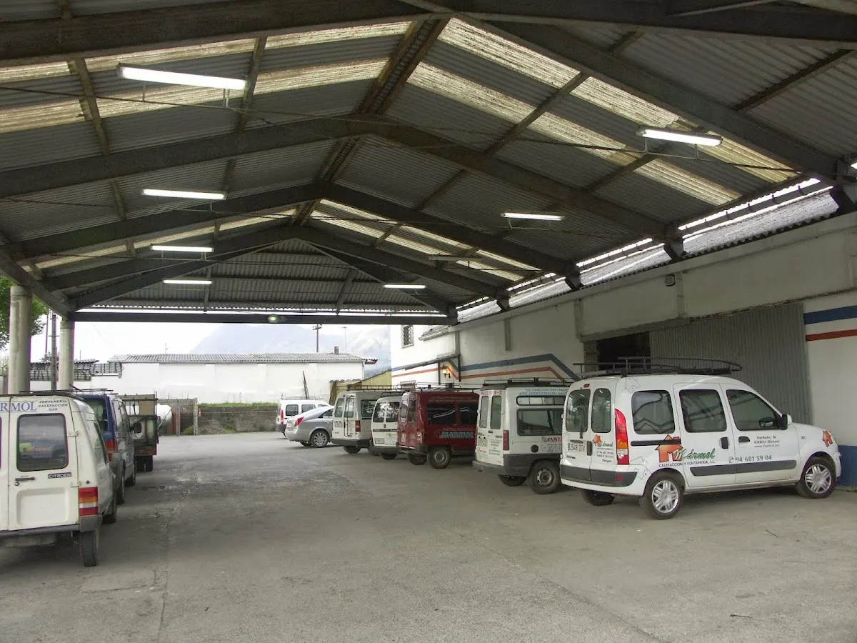 Vehículos de trabajo estacionados bajo la cubierta de las instalaciones de Calefacción y Fontanería Mármol SLU.