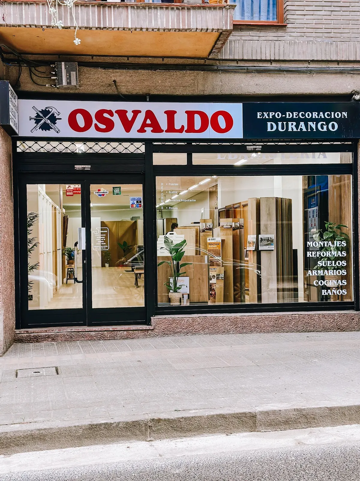 Fachada de la exposición de Carpintería Osvaldo en Durango, con puertas, muebles y otros trabajos visibles en el interior.