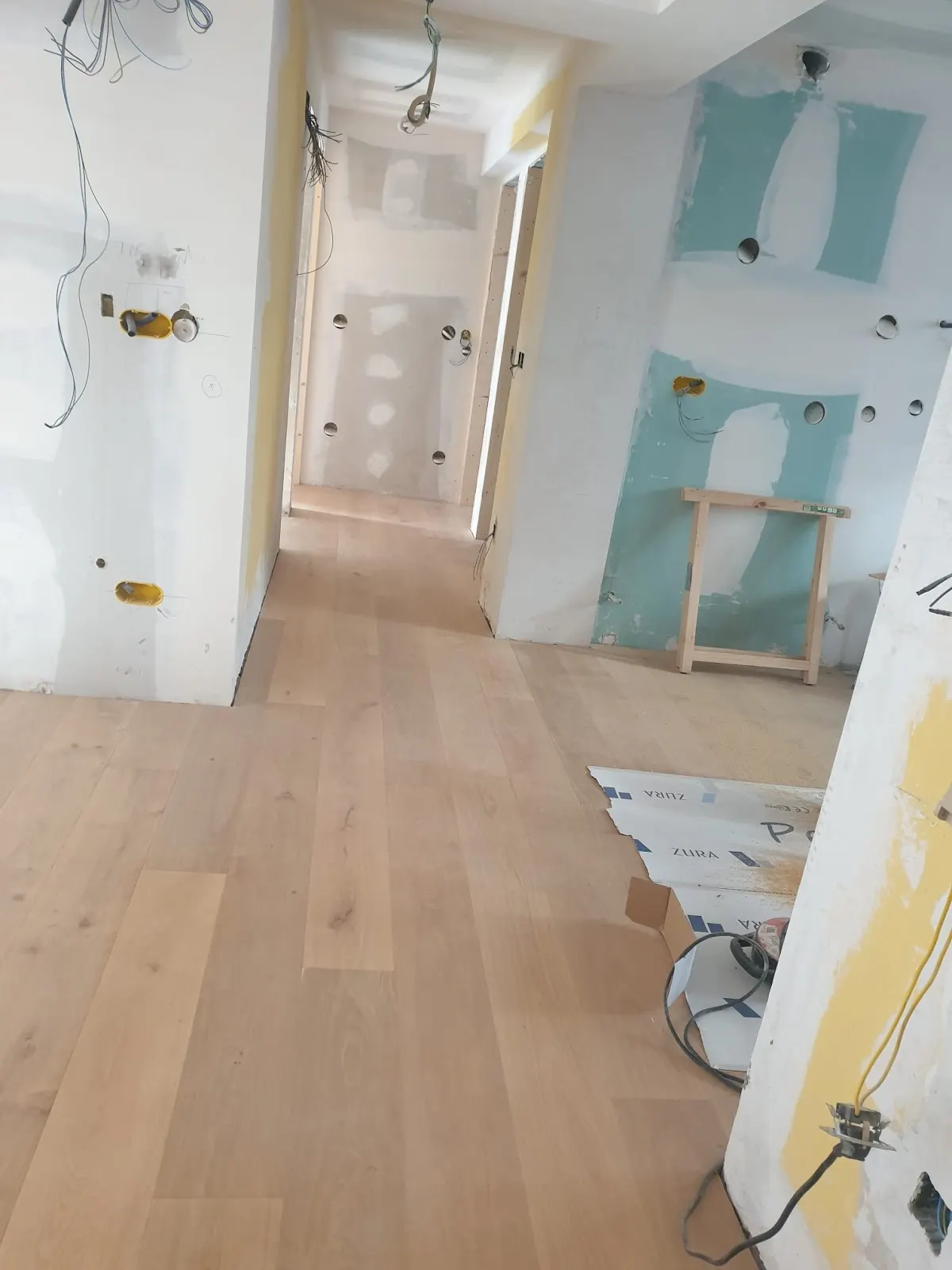 Interior en reforma con suelo de madera y paredes en preparación.