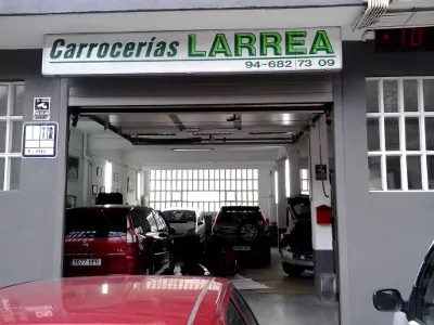 Entrada del taller Carrocerías Larrea en Zaldibar, con varios coches en el interior.