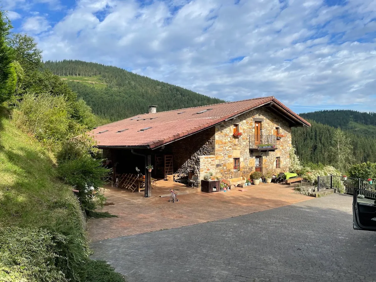 Casa Rural Dukebaso, casa de piedra con tejado rojizo en un entorno de monte