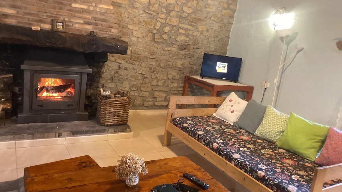 Salón de Casa Rural Dukebaso con chimenea, sofá y paredes de piedra