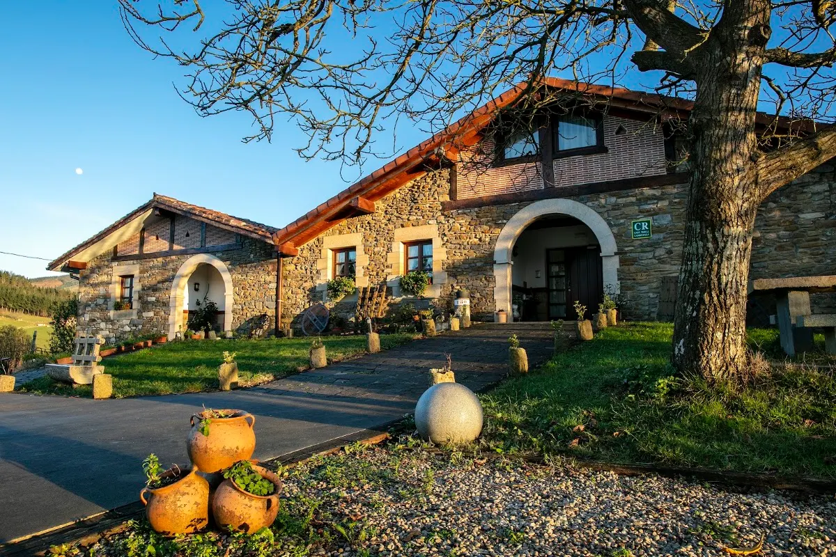 Fachada de piedra de Casa Rural Zelai Landetxea con jardín y árboles