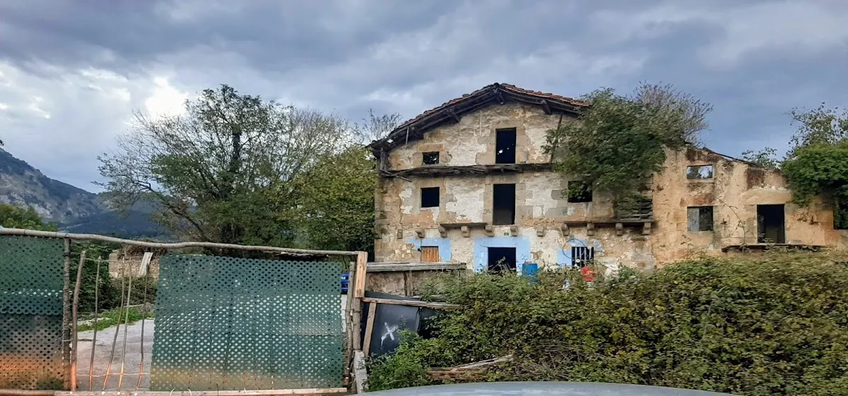 Vista exterior del Caserío Otalora, con vegetación y una entrada vallada