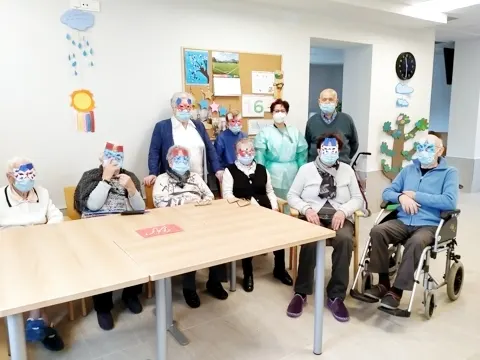 Personas mayores y personal del Centro de Día Eguzkilore reunidos alrededor de una mesa durante una actividad.