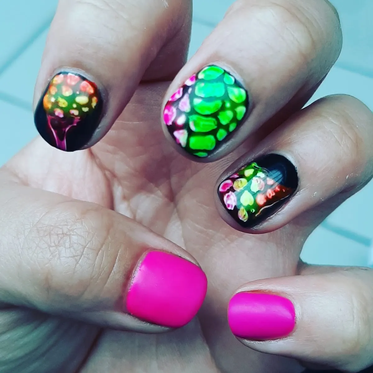 Uñas con diseños de colores y esmalte fucsia, trabajo de Centro de Estética Leire.