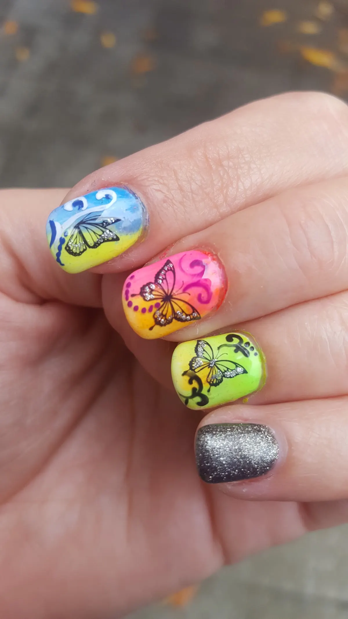 Manicura decorada con mariposas y esmalte de purpurina, trabajo de Centro de Estética Leire.