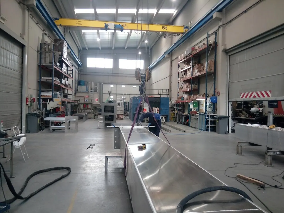 Interior de un taller de CEPRENOR con maquinaria, estanterías y una pieza metálica en primer plano.