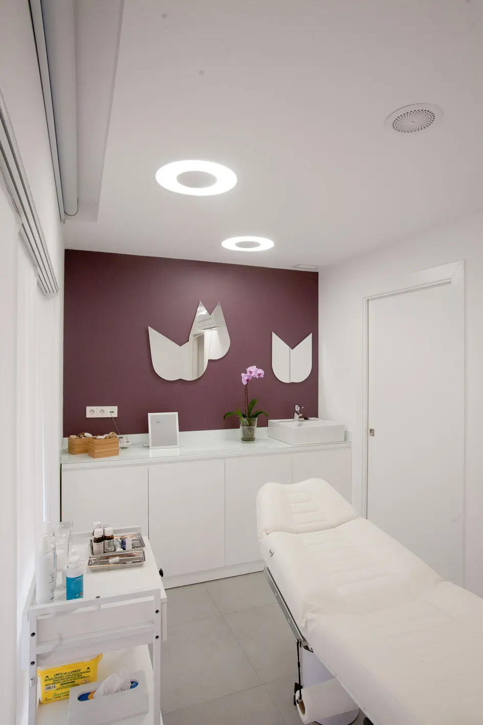 Sala de tratamiento de Clínica Estética Dermodent, con camilla y mobiliario blanco
