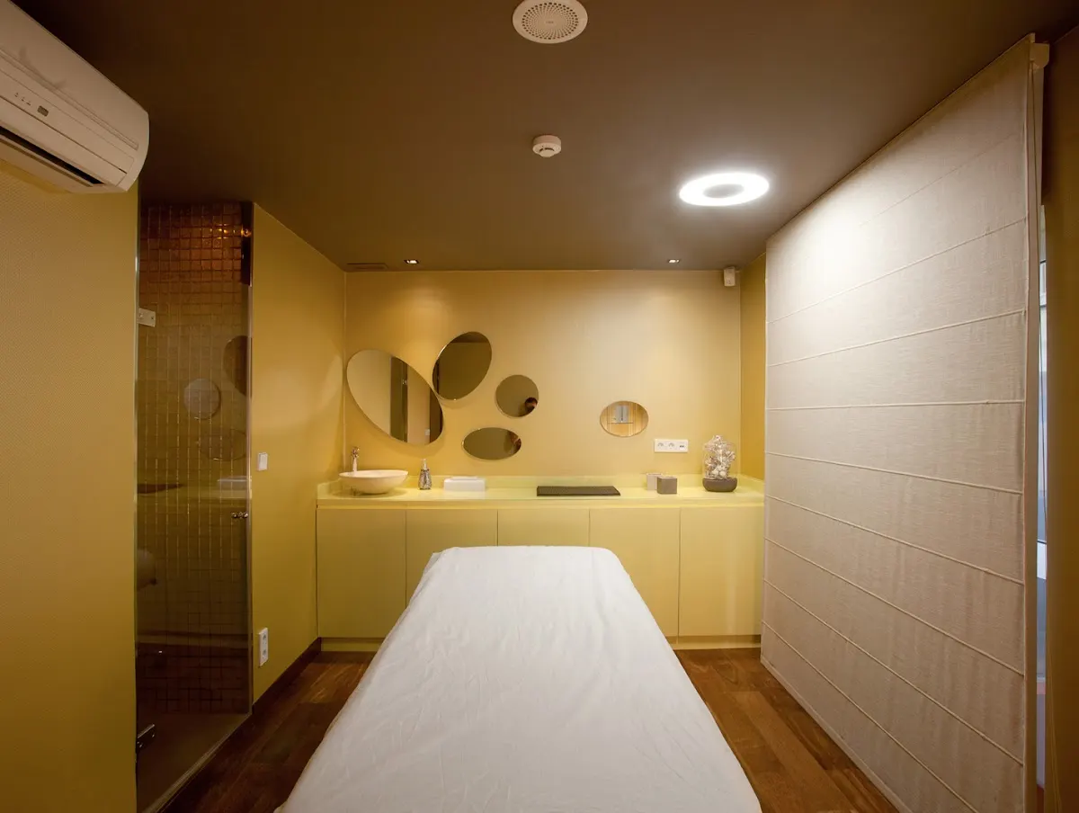 Sala de tratamiento de Clínica Estética Dermodent con camilla y espejos