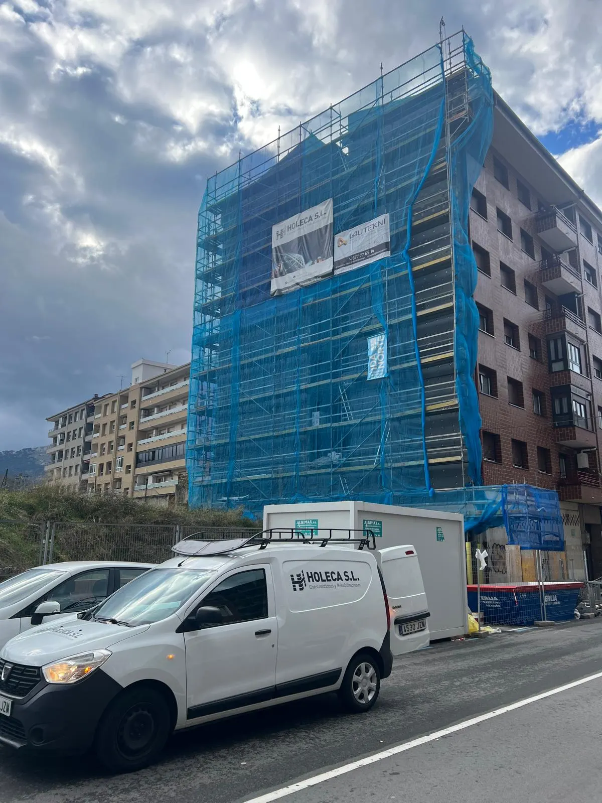Edificio con andamios y vehículo de Construcciones Holeca S.L. en la calle.